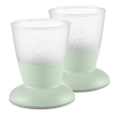 Two green baby cups with white tops on a white background