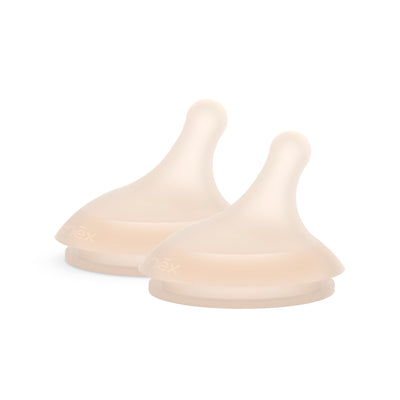 Two beige silicone baby bottle nipples on a white background