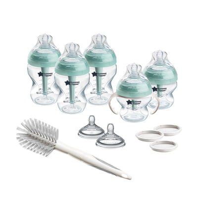 Set of baby bottles, sippy cups, and cleaning brush on a white background
