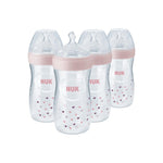 Four NUK baby bottles with pink caps and heart patterns on a white background